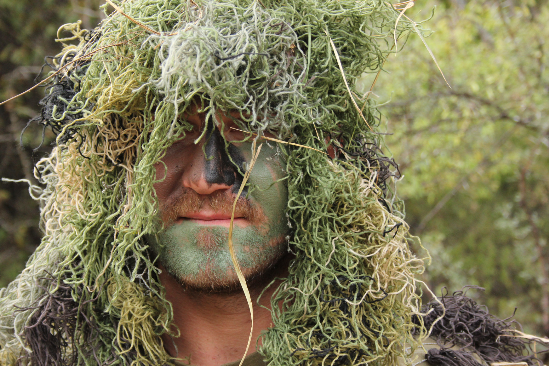 Camouflaged trainee concealed in the bush during anti-poaching field exercises.