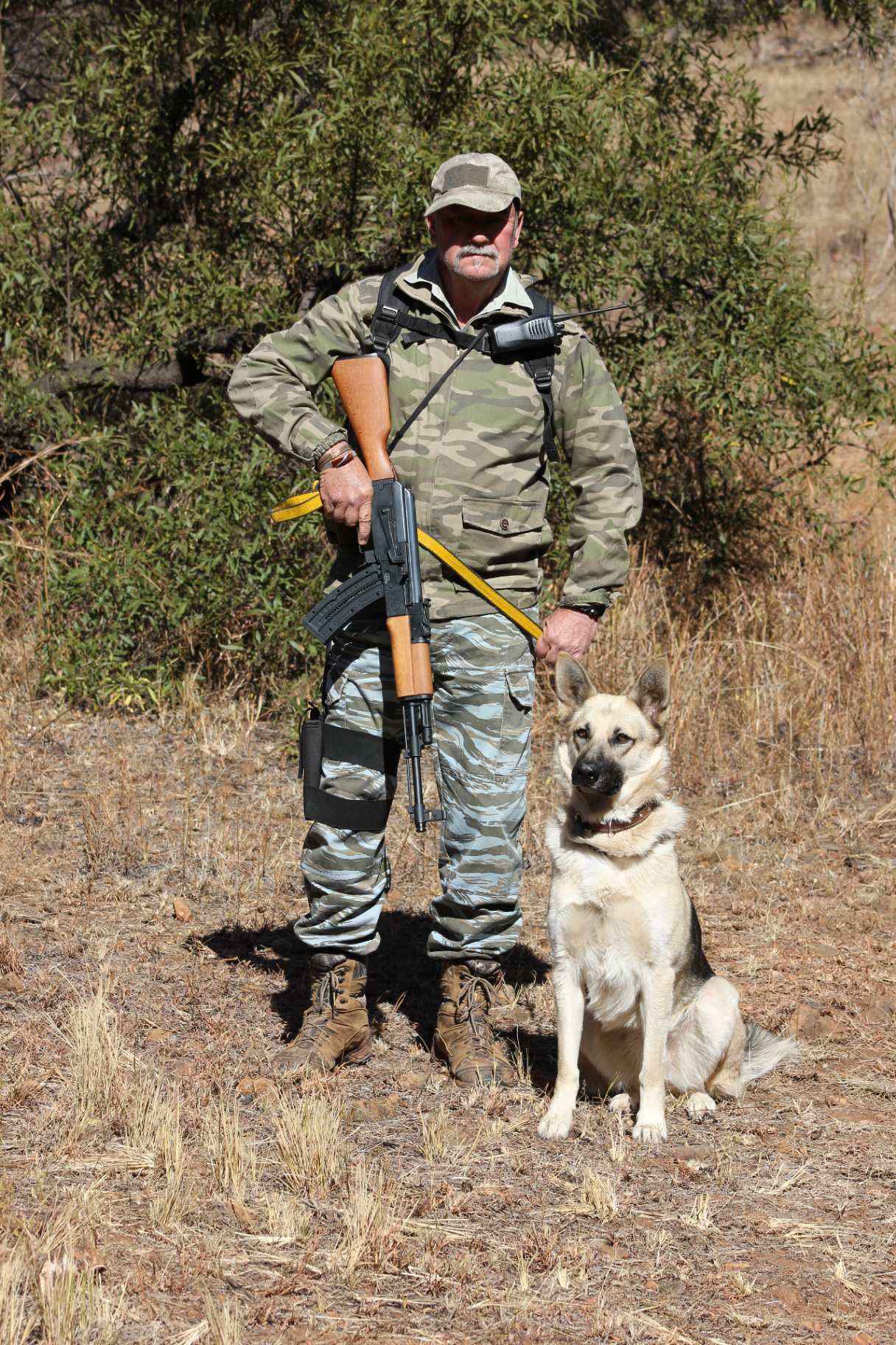 Les Brett standing with a trained working dog in the field.