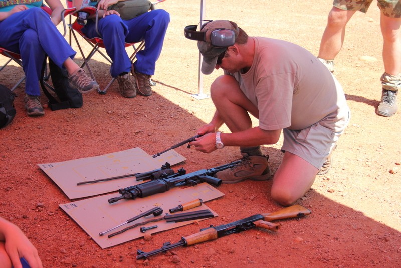 Instructor demonstrating rifle stripping and maintenance to trainees in the field.